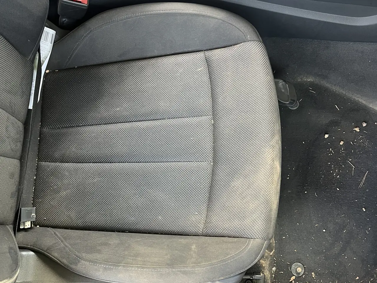 Asiento del conductor y suelo del coche antes de la limpieza, con barro y restos