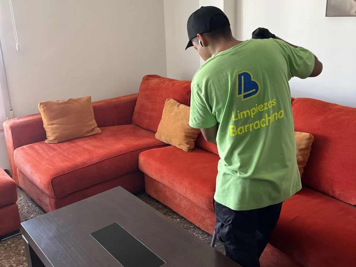 Operario de Barrachina limpiando un sofá de tela naranja